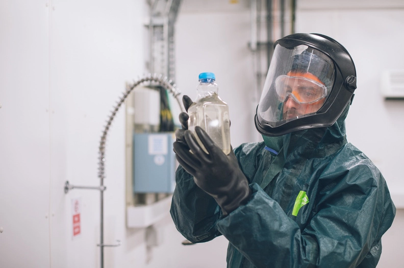 Wessex Water employee in a hazmat suit looking at water sample