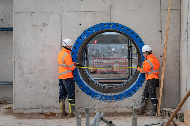 Two employees measuring a wall